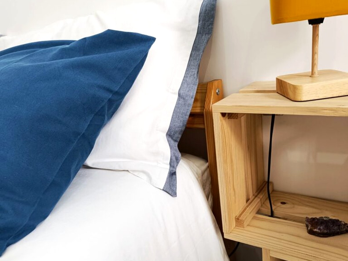 Zona letto con lampada e comodino in legno